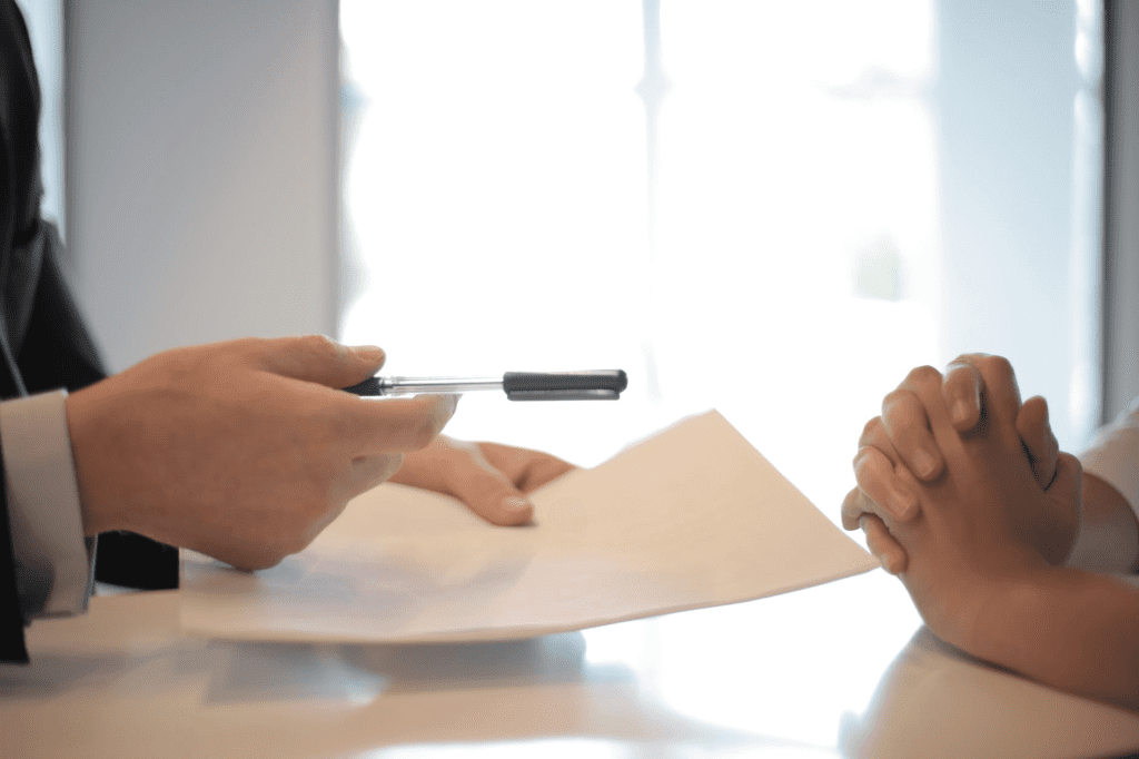 A person holding a pen and a piece of paper for contract signature