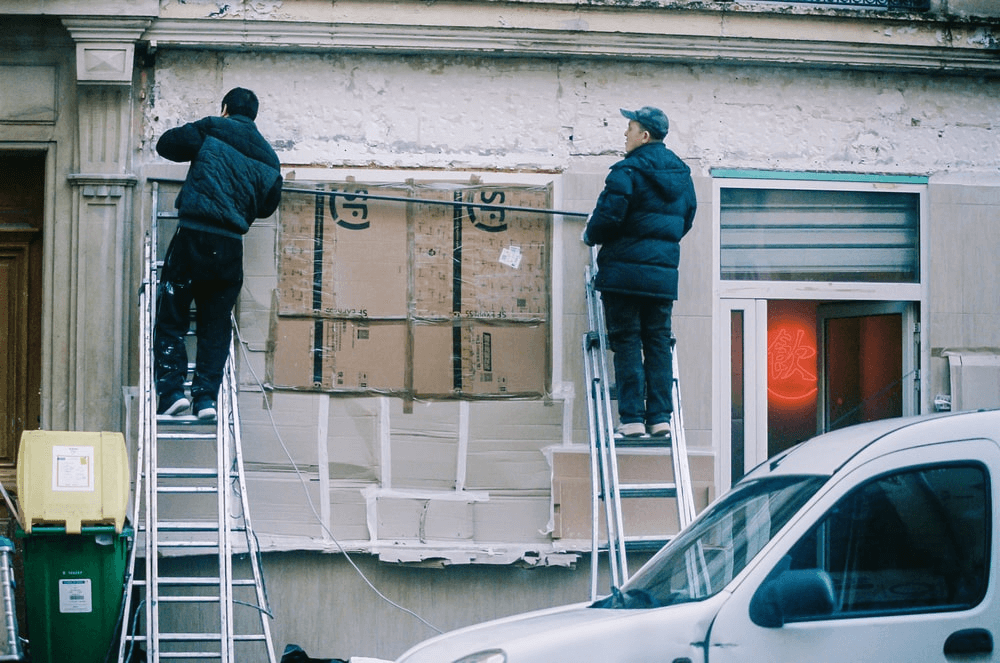 Two workers fixing the exterior of the building