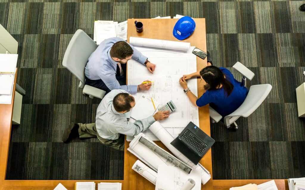 A group of people sitting around a table with blueprints.