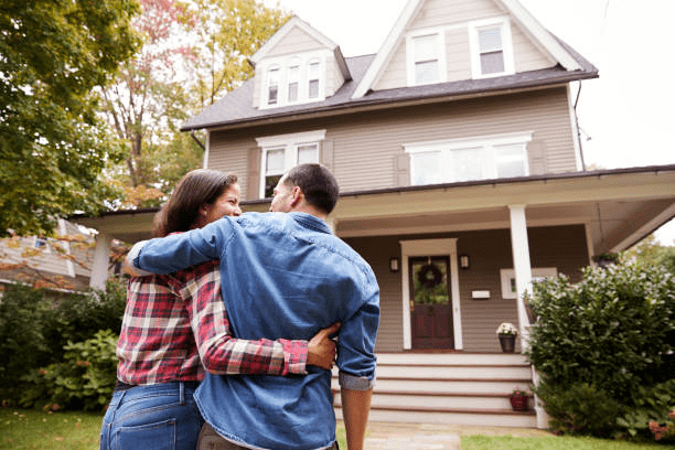 A couple standing in front of their home