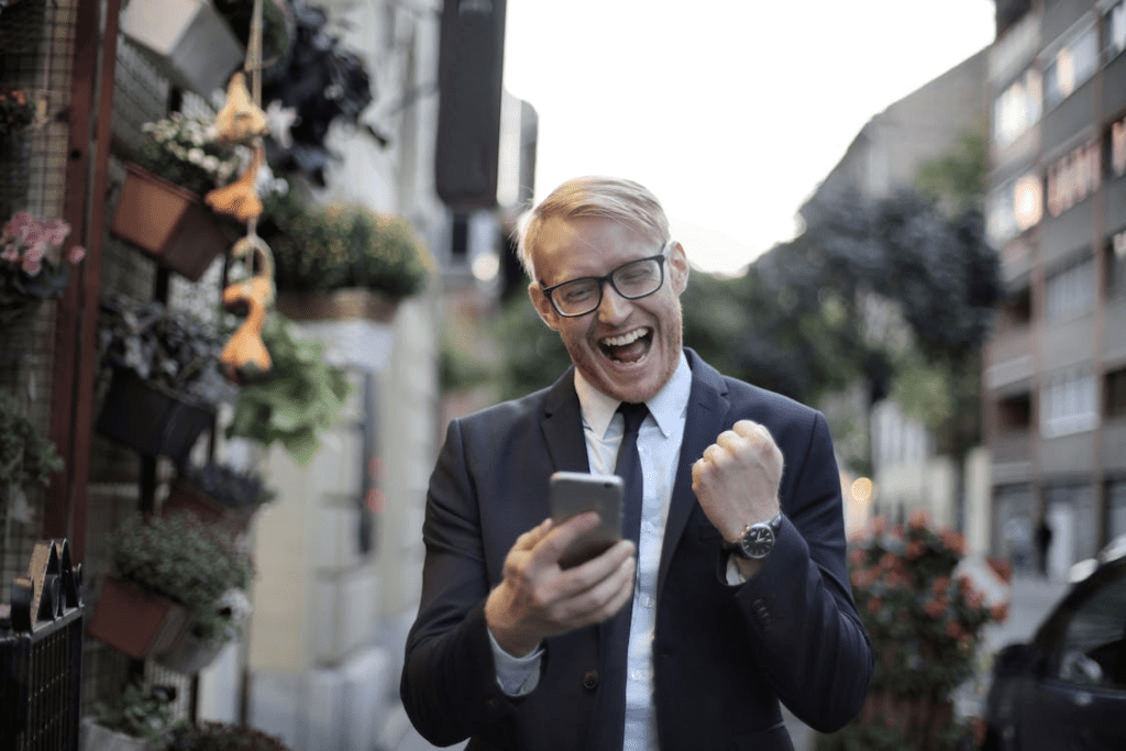 A photo showing a person in a black suit holding a smartphone.