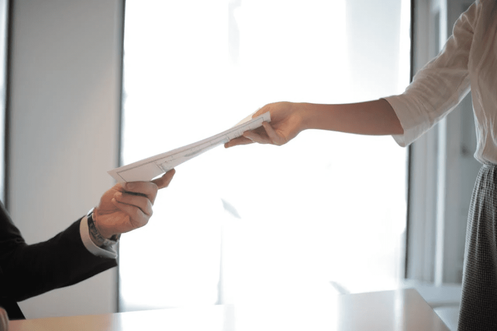 A photo showing two people exchanging a document.