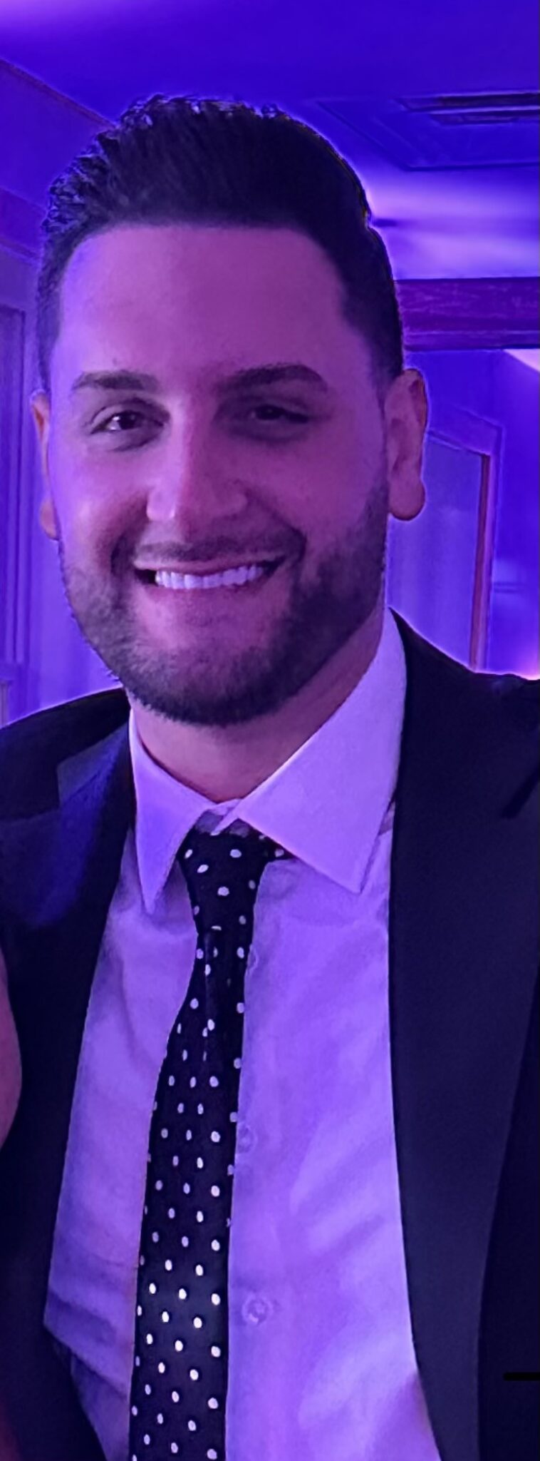 A man in a suit and tie smiles for the camera.