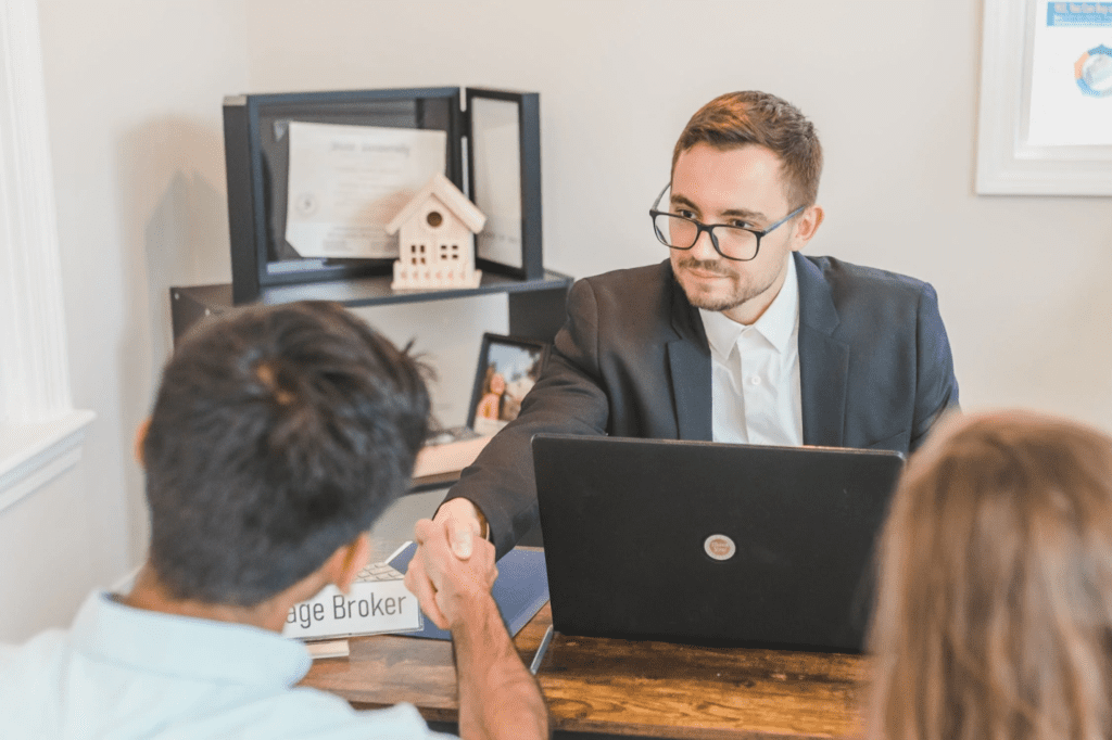 A photo showing a couple conversing with a man from across a desk.