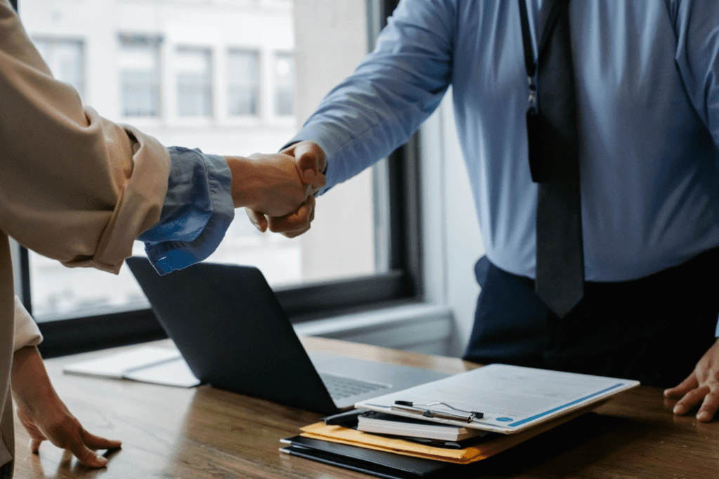 A photo showing two people shaking hands over a table.