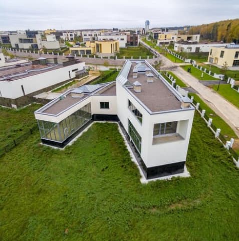 Modern suburban home featuring a unique angular design with a grassy yard, viewed from above.