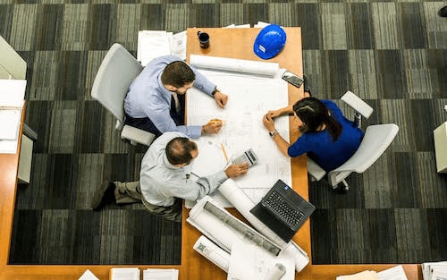 People reviewing a blueprint before granting a new construction loan