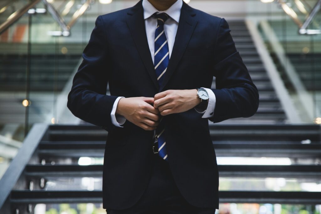 A person in a business suit fastening a button, standing before an escalator, specializing in commercial bridge loans.