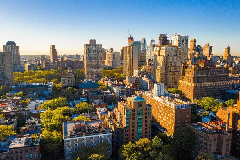 Aerial view of an urban skyline with high-rise buildings bathed in the warm light of the setting sun.