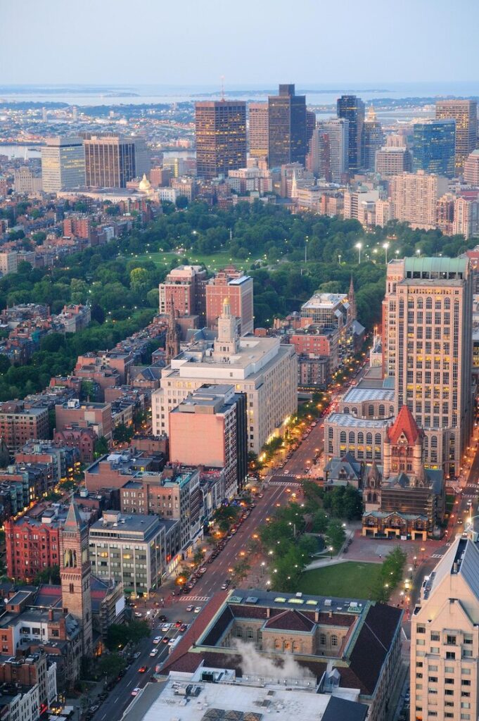 Aerial view of a cityscape during twilight showing illuminated streets and a mix of modern and historic buildings.