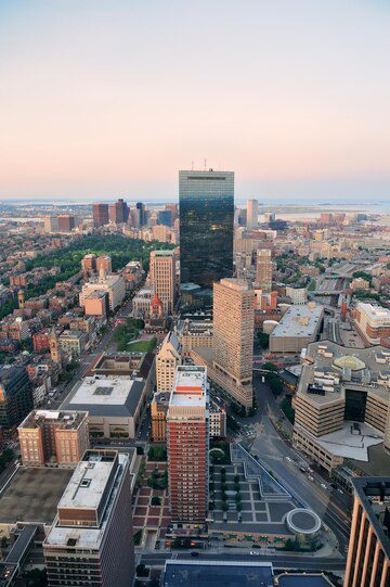 Aerial view of a cityscape at dusk, showcasing a prominent skyscraper and surrounding buildings with a coastal backdrop.