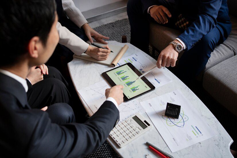 Business professionals discussing graphs and data on a digital tablet during a meeting.