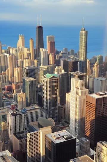 Aerial view of a dense urban skyline with skyscrapers under a blue sky.