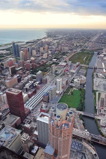 Aerial view of a cityscape with skyscrapers and a river running through it at dusk.