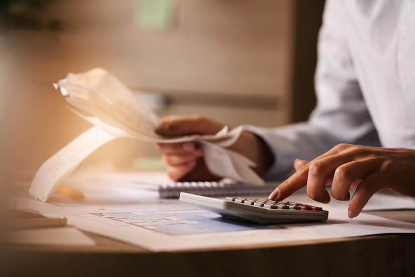 Person calculating finances with a calculator and paperwork.