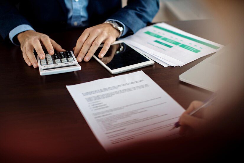 Person using a calculator and examining documents on a desk.