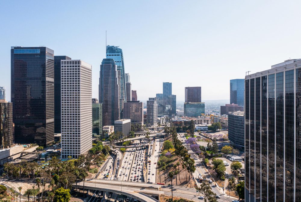 Aerial view of a modern downtown district with skyscrapers and a busy highway.