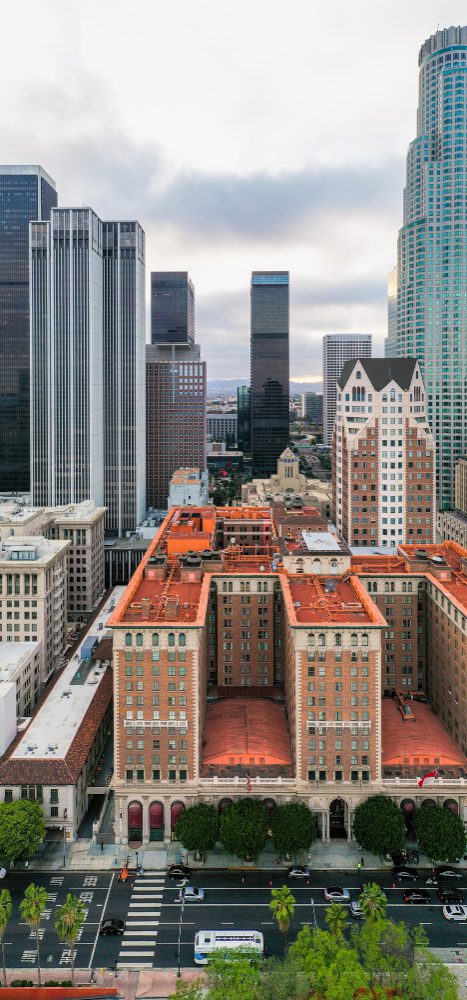 Aerial view of an urban landscape with a historic red-roofed building surrounded by modern skyscrapers.