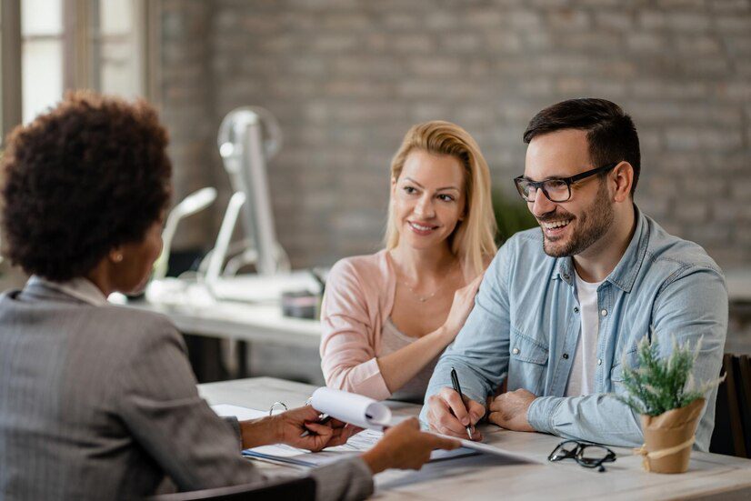 Three professionals having a discussion around a table in an office setting.