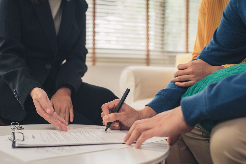 Two individuals reviewing and signing a document at a table.