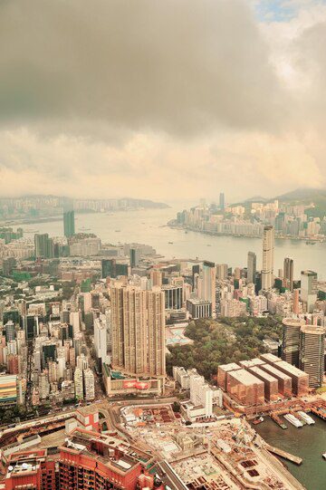 Aerial view of a densely packed urban area with high-rise buildings along a coastline under a hazy sky.