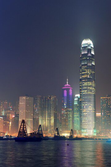 Hong kong skyline at night with illuminated skyscrapers and cranes.