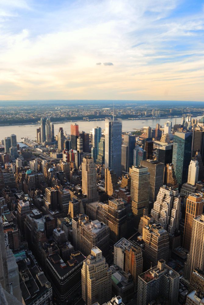 Aerial view of a dense urban skyline with skyscrapers, under a partly cloudy sky.