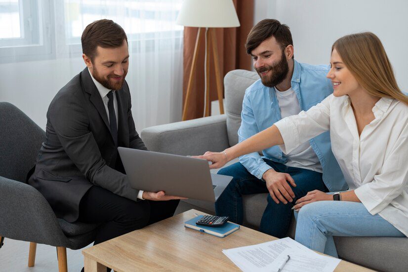 Financial advisor showing a presentation on a laptop to a young couple in a modern office.