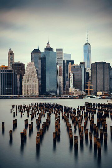 New york city skyline viewed across water with remnants of old piers in the foreground.