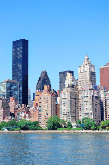 Skyscrapers and buildings along a city waterfront under a clear blue sky.