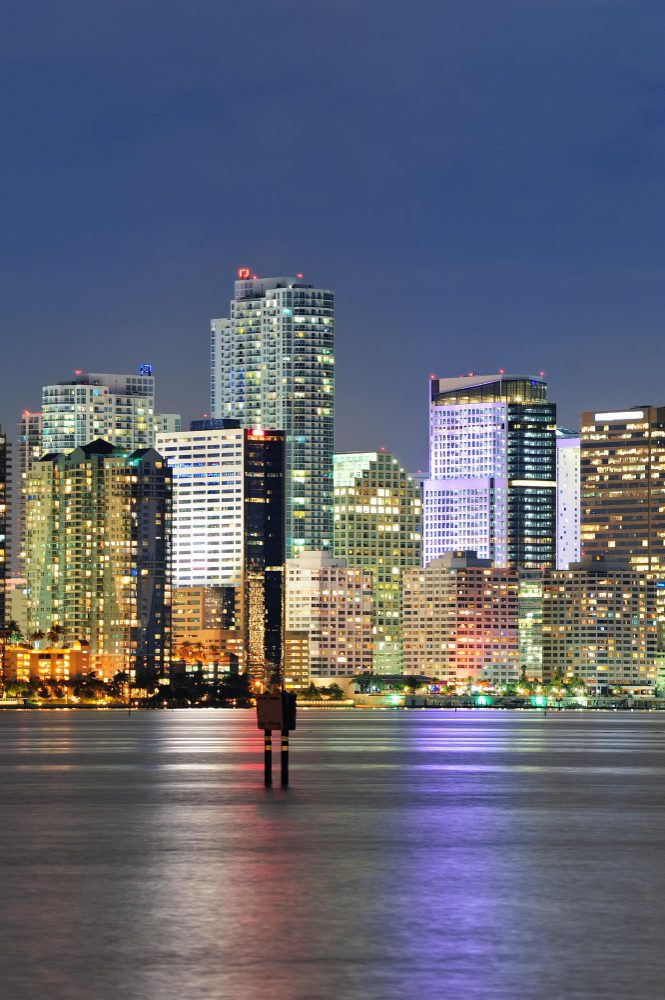 City skyline at night reflecting on water.