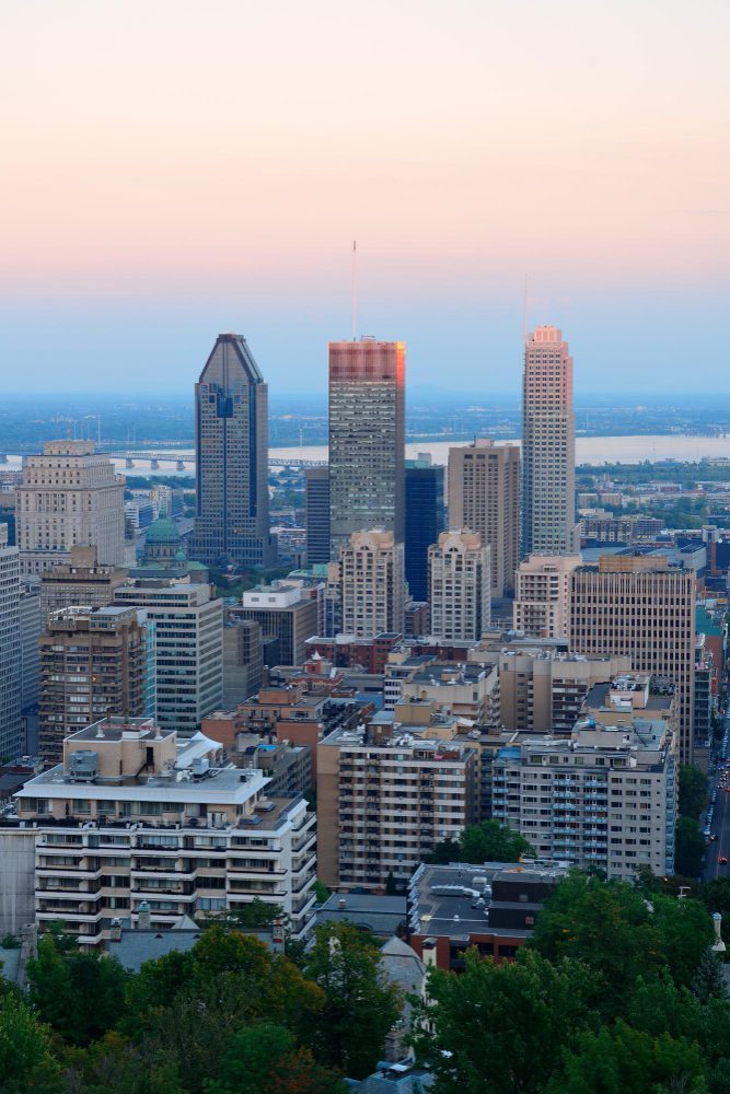 Downtown city skyline at twilight with high-rise buildings and soft pink hues in the sky.