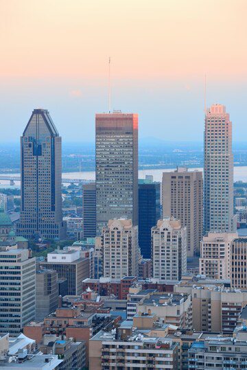 Montreal skyline at dusk with prominent skyscrapers against a soft sky.