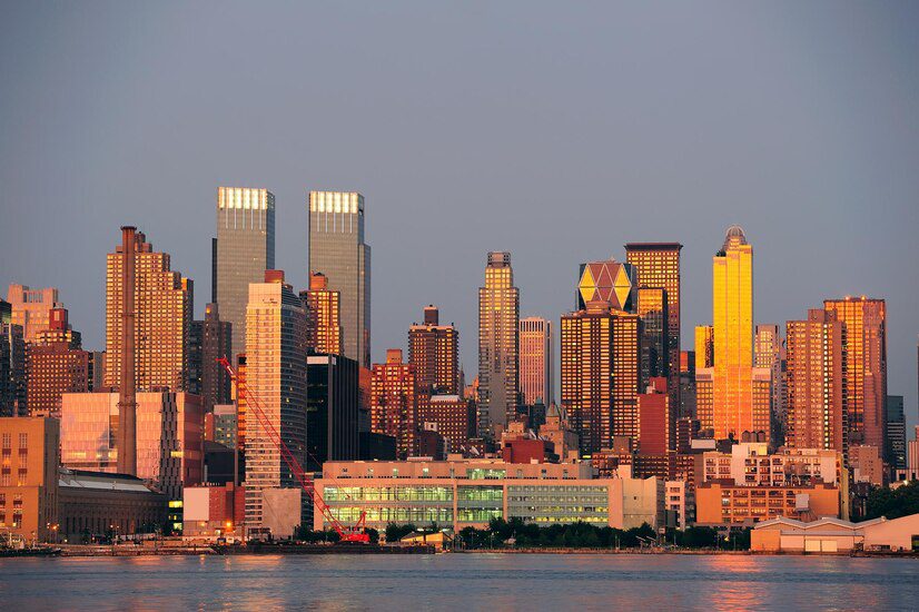 Sunset light reflecting off a city skyline with waterfront buildings in the foreground.