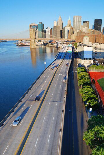 An elevated view of a highway leading towards a city skyline with clear blue skies.