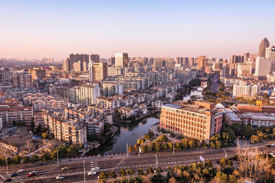 Aerial view of a sprawling urban cityscape at dusk with buildings and a roadway.