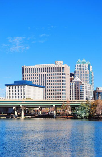 Urban skyline with a bridge over water against a blue sky.