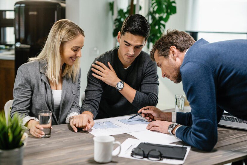 Three professionals collaborating and reviewing documents at a meeting table.