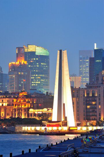 Shanghai's waterfront at dusk with the prominent monument to the people's heroes and illuminated city skyline.