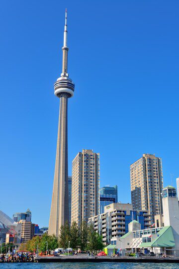 The cn tower dominates the skyline amid surrounding buildings on a clear day.