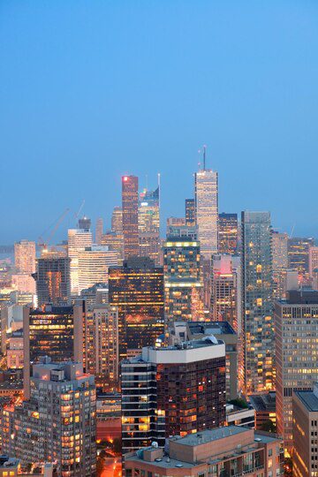 Twilight cityscape with illuminated skyscrapers and dense urban architecture.