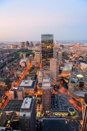 Aerial view of a city at dusk with illuminated buildings and streets.