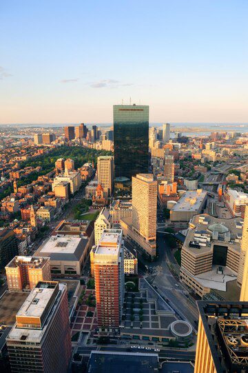 Aerial view of a downtown cityscape at sunset with a prominent skyscraper and surrounding buildings.