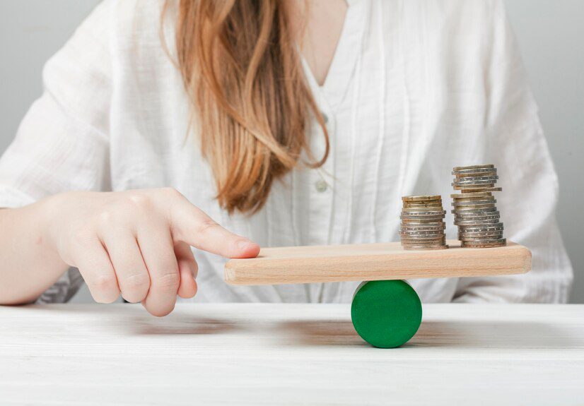 Person balancing coins on a seesaw to illustrate financial stability or budgeting.