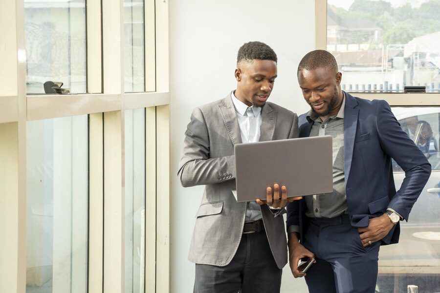 Two professionals discussing over a laptop in an office setting.