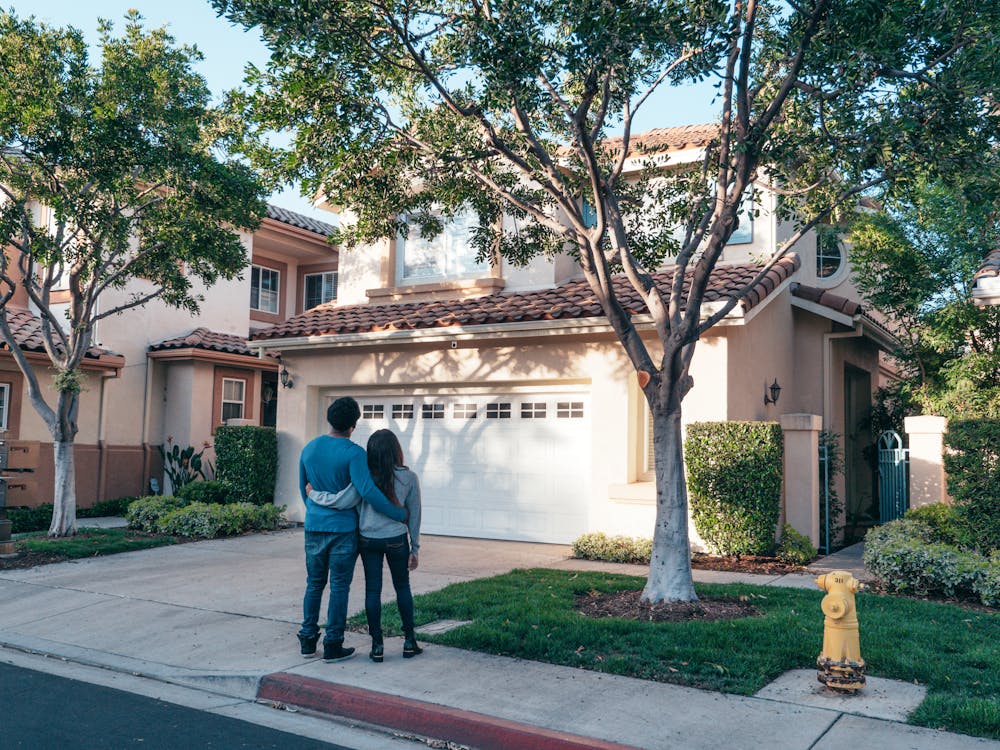 Happy couple standing in front of their newly constructed house