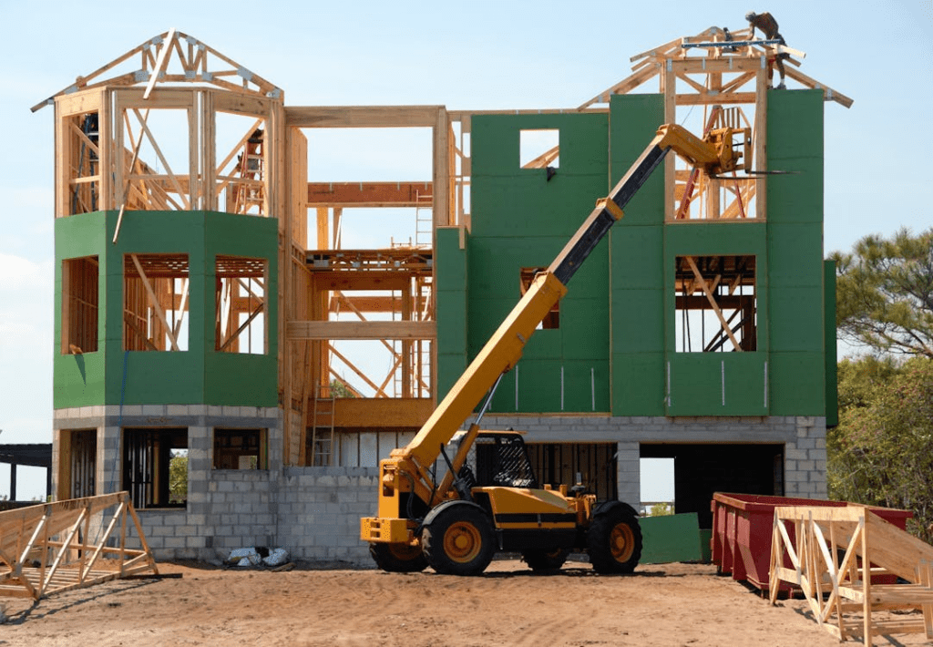 A yellow and black heavy equipment near unfinished building