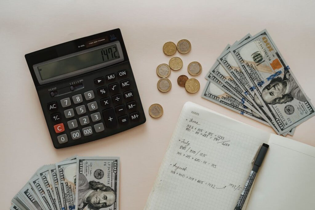 A calculator next to a notebook and some money