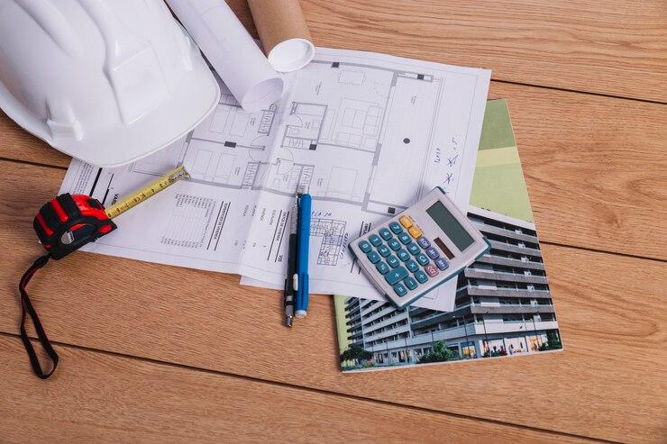 Blueprint with a calculator and construction helmet on a desk