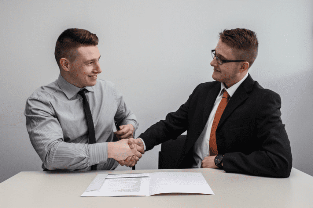 A photo showing two people shaking hands at a table.